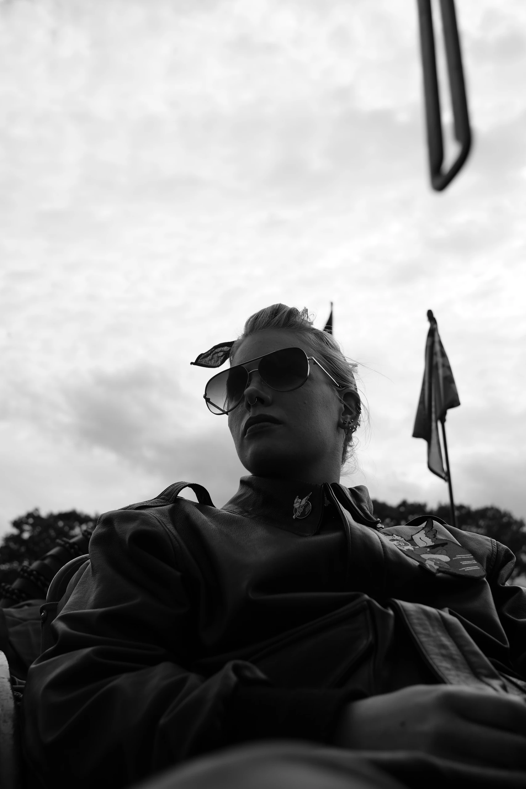 Black-and-white portrait of a woman in sunglasses against a cloudy sky